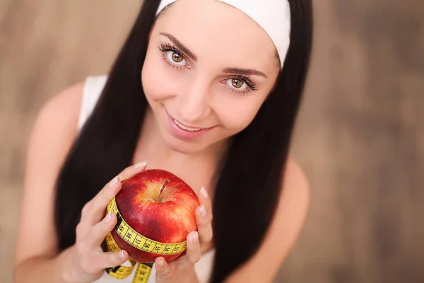 Hermosa mujer sosteniendo y midiendo manzana con cinta métrica —  Fotos de Stock