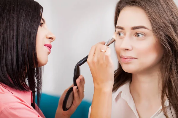 Maquillaje artista hace maquillaje a una hermosa chica en un salón de belleza — Foto de Stock