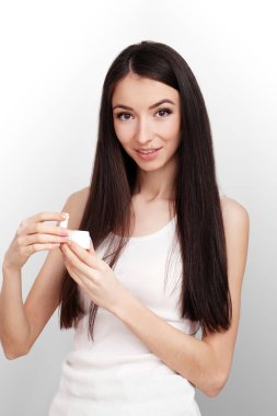 Güzel genç kadın onun yanak kemiği yüz kremi uygulamak bir