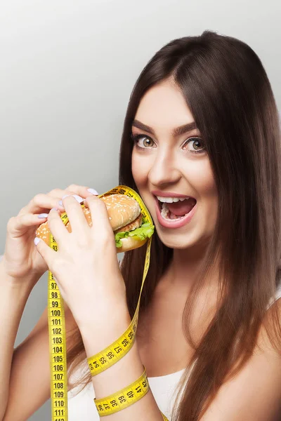 Slimming A young girl eats a burger. Against excess weight. The — Stock Photo, Image