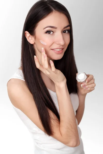 Mulher bonita aplicando creme facial em seu osso da bochecha em um — Fotografia de Stock