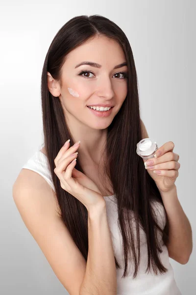 Bella giovane donna che applica la crema viso al suo osso della guancia in un — Foto Stock