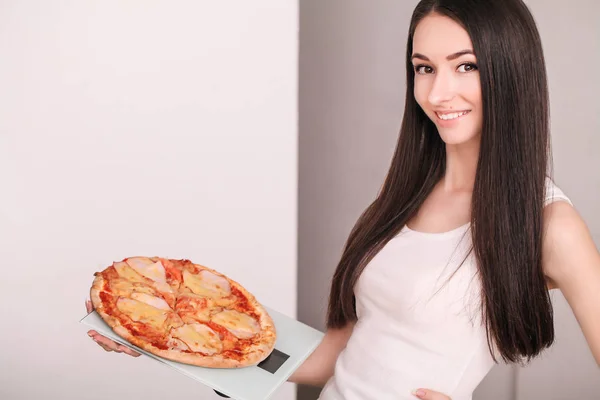 Régime alimentaire. Jeune belle fille pesant balance tenant pizza. Le con — Photo