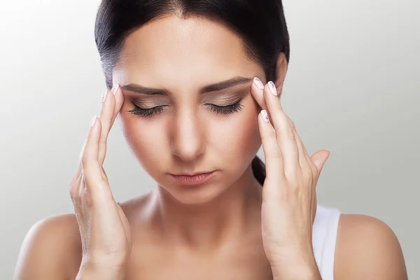 Ból. Młoda kobieta z bólem głowy, który trzyma głowę, szary — Zdjęcie stockowe