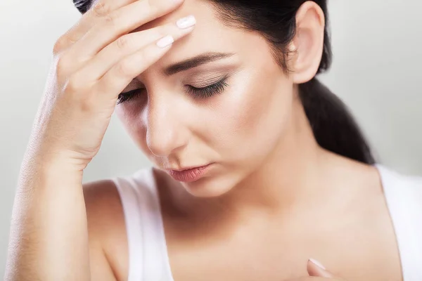 Portrait of a beautiful young brunette with bare shoulders, severe headaches, migraine, colds. The concept of treatment. Holds his hand to his forehead. — Stock Photo, Image