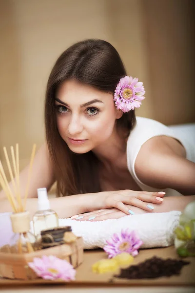 Wellness-Behandlungen. schönes junges Mädchen auf einem Massagetisch liegend. Aromaöl.Saubere und gepflegte Haut. Schönes Lächeln. Vorstellung von Schönheit und Gesundheit. — Stockfoto