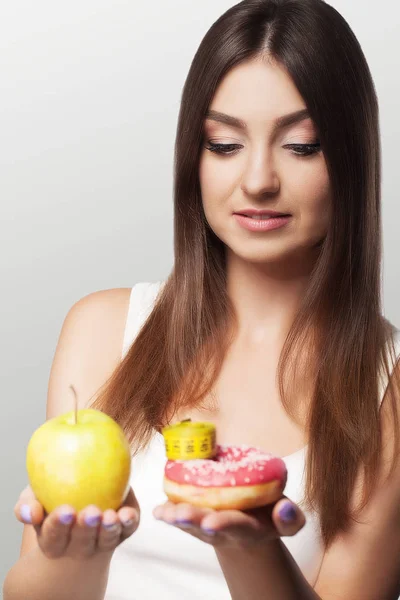 Una mujer joven hace una elección entre alimentos saludables y dañinos. S —  Fotos de Stock