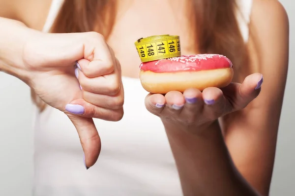 Dieta. Donut no. Una joven sostiene un donut en su mano y muestra — Foto de Stock
