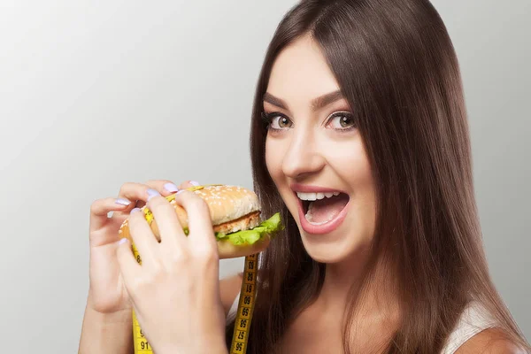 Mănâncă hamburger O fată tânără cu poftă de mâncare mănâncă un hamburger. Dieta . — Fotografie, imagine de stoc