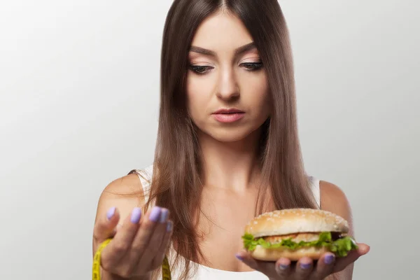 A young woman makes a choice between healthy and harmful food. S — Stock Photo, Image