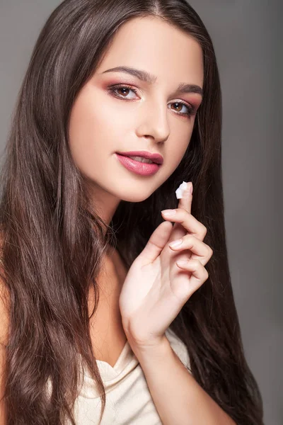 Smiling pretty woman applying cream on her face — Stock Photo, Image