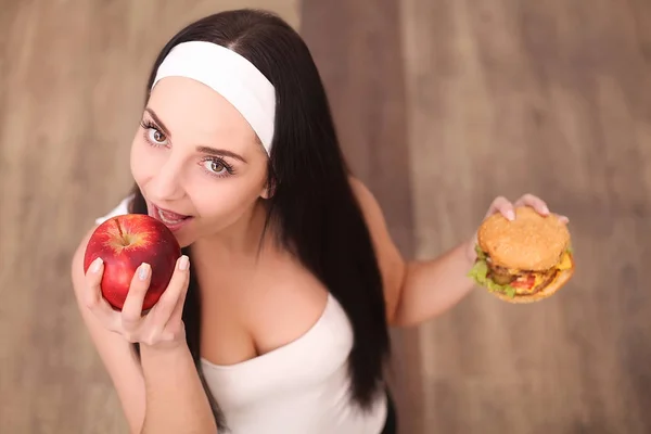 Femme saine sentant le hamburger et tenant la pomme — Photo