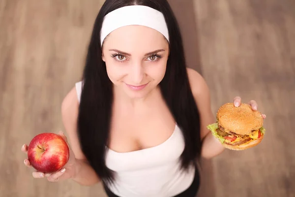 Santé, alimentation et concept alimentaire - femme saine sentant le hamburger et tenant la pomme — Photo