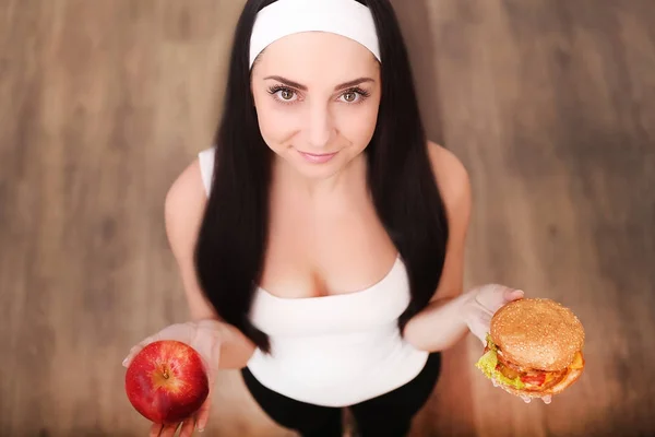 Gesunde Frau riecht Hamburger und hält Apfel — Stockfoto