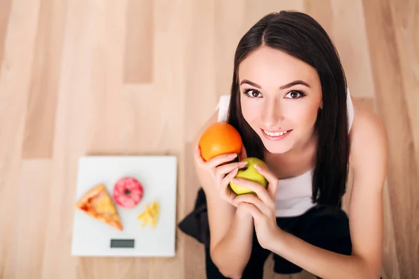 Mulher desportiva com escala e maçã verde e laranja — Fotografia de Stock