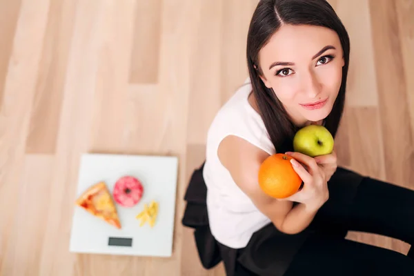 Mujer deportiva con escamas y manzana verde y naranja —  Fotos de Stock