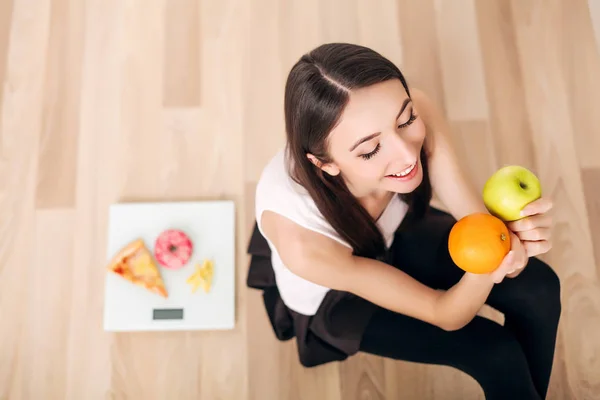 Sporty woman with scale and green apple and orange — Stock Photo, Image