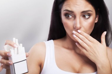 Bir paket sigara bir kadın elinde. Sigara hayret göz. Sağlık koruma kavramı sigara karşı. Gri bir arka plan üzerinde.