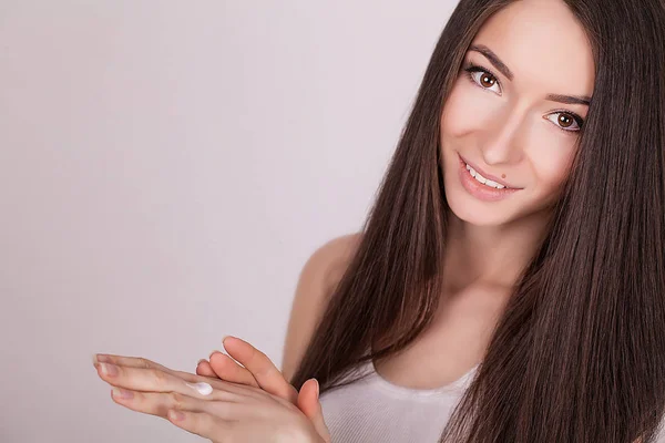Anwendung kosmetischer Creme. eine schöne junge Frau, die Gesichtsfeuchtigkeitscreme aufträgt. Pflegen des Gesichts und der Hände — Stockfoto