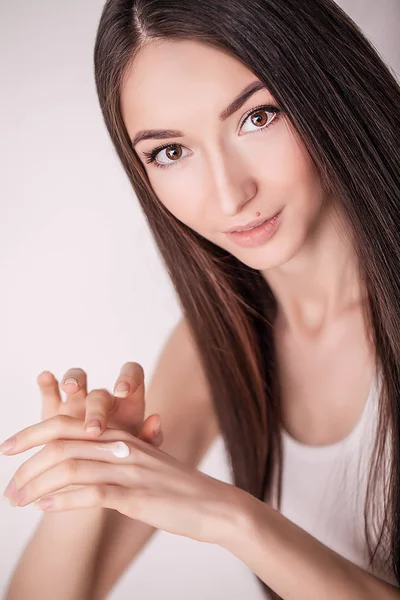 Anwendung kosmetischer Creme. eine schöne junge Frau, die Gesichtsfeuchtigkeitscreme aufträgt. Pflegen des Gesichts und der Hände — Stockfoto