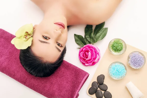 Spa, beauty, people and body care concept - красивая женщина, получающая лечение лица на праздничном световом фоне — стоковое фото