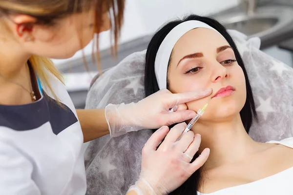 La mujer se inyecta en la cara. Mujer de belleza dando inyecciones. Mujer joven recibe inyecciones faciales de belleza en el salón de cosmetología. Inyección de envejecimiento facial. Medicina estética, Cosmetología — Foto de Stock