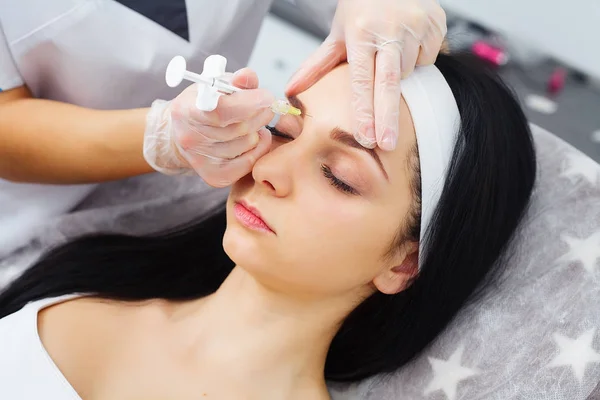 Manos del cosmetólogo haciendo inyección en la cara, labios. Mujer joven recibe inyecciones faciales de belleza en el salón. Procedimientos de envejecimiento facial, rejuvenecimiento e hidratación. Cosmetología estética. De cerca.. — Foto de Stock