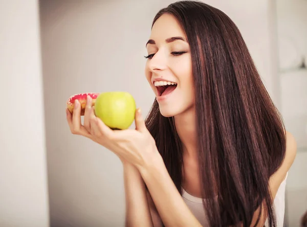 Dieta. Una mujer joven sosteniendo una pizza en la balanza y hacer una elección entre una manzana y un donut. El concepto de alimentación saludable —  Fotos de Stock