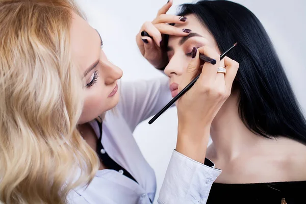 Maquiagem artista faz maquiagem para uma menina bonita em um salão de beleza — Fotografia de Stock