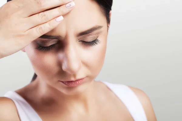 Mal di testa in una ragazzina. Emicrania. Stanchezza dopo una dura giornata di lavoro. Il concetto di salute. Su uno sfondo grigio . — Foto Stock