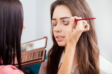 Genç, güzel bir kız bir güzellik salonunda makyaj yapıyor.