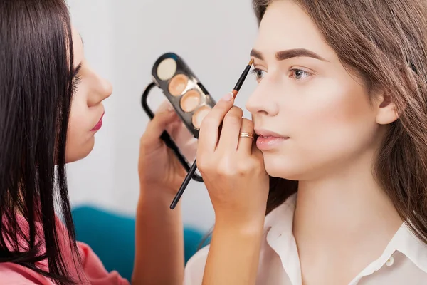 Akeup artist trägt make-up für attraktive brünette mädchen am m — Stockfoto
