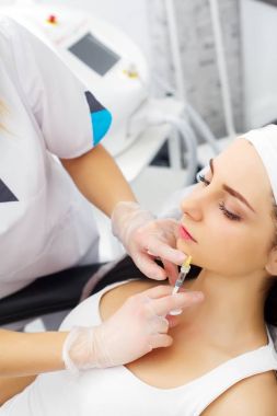 Çok beyaz kadın hyaluronik asit enjeksiyon yüz bölgesinde sahip. Kadının yüzüne kollajen ile doldurma şırınga ile erkek doktor. Gençleştirme tedavisi kavramı.