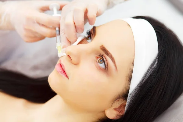 Mujer bastante caucásica que se inyecta ácido hialurónico en la zona de la cara. Médico varón con jeringa llenando la cara de la mujer con colágeno. Concepto de terapia de rejuvenecimiento . — Foto de Stock