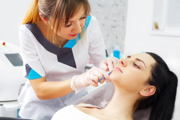 Mujer bastante caucásica que se inyecta ácido hialurónico en la zona de la cara. Médico varón con jeringa llenando la cara de la mujer con colágeno. Concepto de terapia de rejuvenecimiento . — Foto de Stock