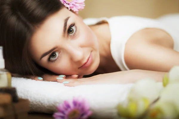 Porträt eines schönen Mädchens in einem Wellnessbereich. Sanfter Blick. Blumen im Haar. Aromaöl. Massageschrank. das Konzept der Gesundheit und Schönheit. — Stockfoto