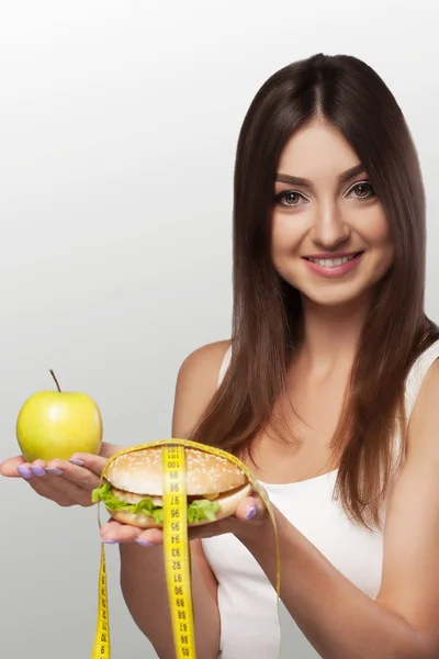Hands offer an apple (healthy food) and cakes (unhealthy food) t — Stock Photo, Image