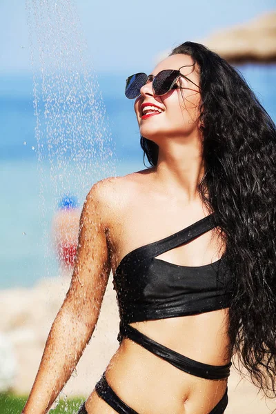 Mujer hermosa tenned en bikini negro y gafas de sol sentado en — Foto de Stock