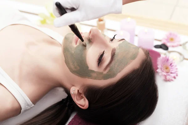 Terapia de spa para mulher jovem com máscara facial no salão de beleza — Fotografia de Stock