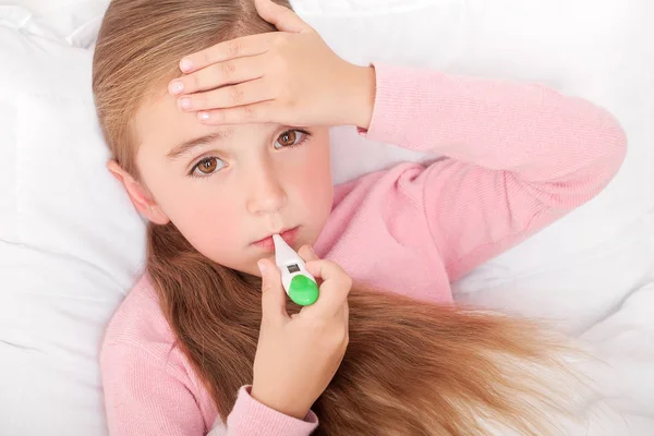 Gripe. Chica joven acostada en la cama con un termómetro — Foto de Stock