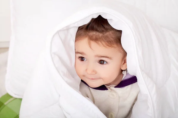 フェザーベッディングの下でベッドに横たわっている女の赤ちゃんの肖像画 — ストック写真