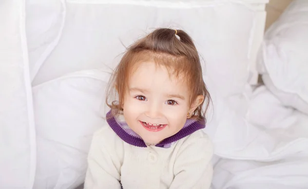 Retrato de menina deitada na cama sob pena — Fotografia de Stock