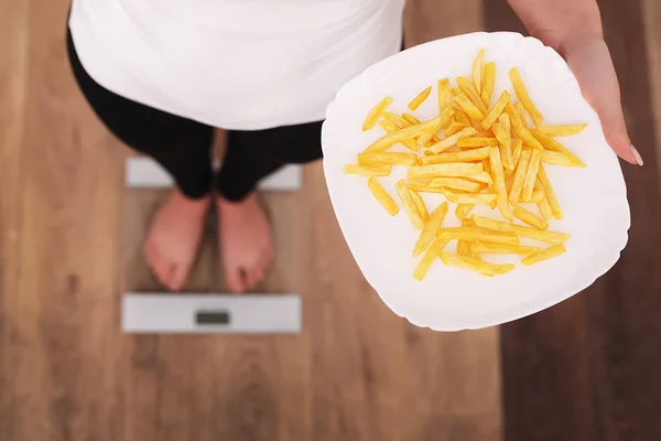 Mulher bonita jovem de pé em escamas e segurando uma batata frita. O conceito de alimentação saudável. Estilo de vida saudável. Dieta . — Fotografia de Stock