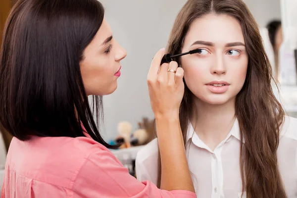 Nahaufnahme der Hand einer asiatischen Frau, die Lidschatten auf das weibliche Auge aufträgt — Stockfoto