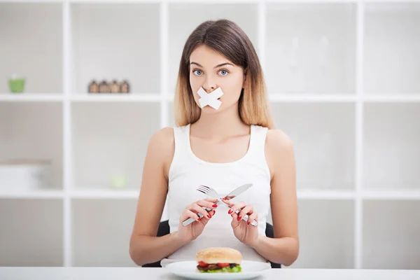 Diet. Young woman with duct tape over her mouth, preventing her