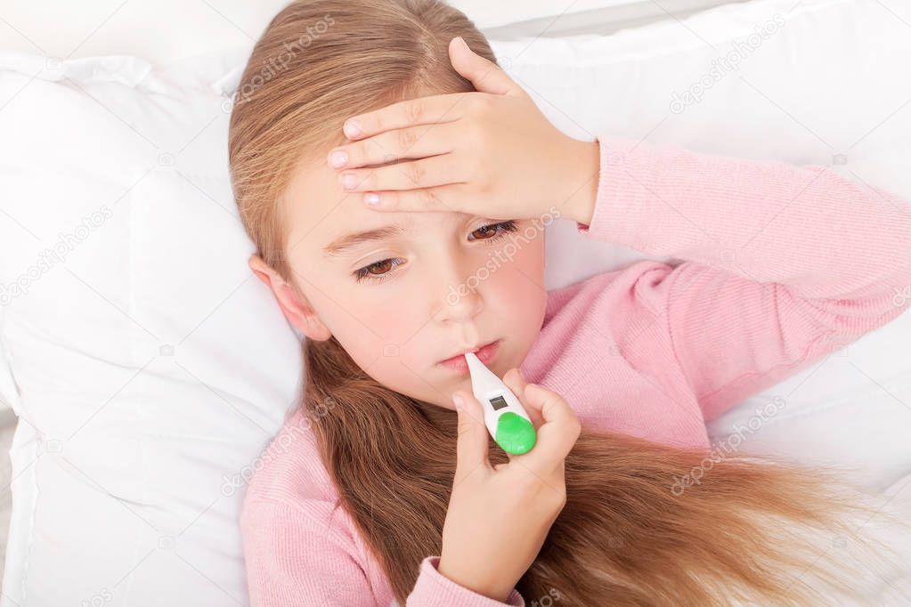 Flu. Young girl lying in bed with a thermometer