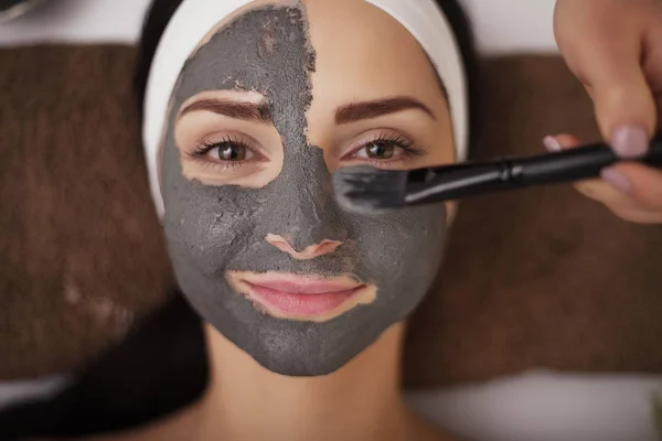 Primer plano de la mano la aplicación de la máscara facial a la cara de la mujer en la belleza sa — Foto de Stock