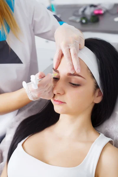 Primer plano de hermosa mujer joven recibe la inyección en los ojos y los labios — Foto de Stock