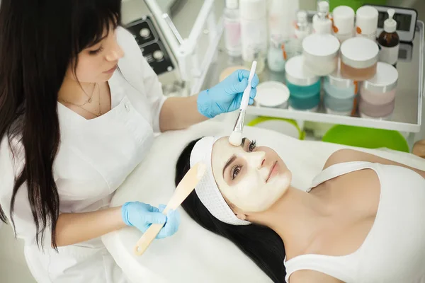 Schoonheidsspecialist gezichtscrème toe te passen op de client in de cosmeto — Stockfoto
