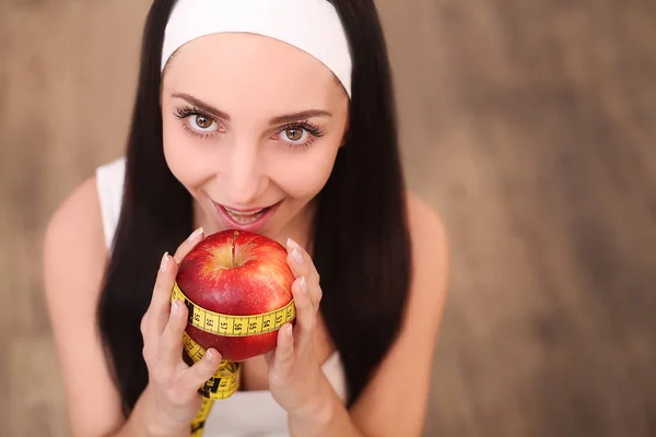 Joven mujer bonita está sosteniendo manzana y cinta métrica. Concepto de comida saludable . —  Fotos de Stock